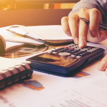 Woman using calculator with doing finance at home office. ¿Reprogramar deudas afecta tu historial crediticio?