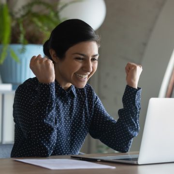 Emotional,Euphoric,Young,Indian,Ethnic,Businesswoman,Looking,At,Laptop,Screen, ¿Te encuentras en una central de riesgo?, Conoce las ventajas de estar ahí