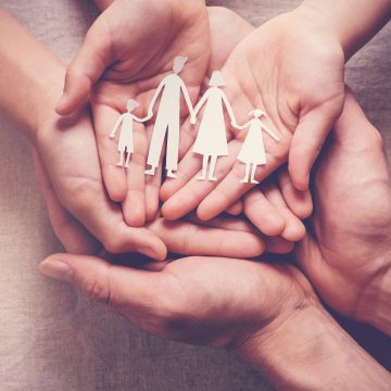 Adult and children hands holding paper family cutout, family home, foster care, homeless charity support concept Resultados financieros 2020 de MAPFRE: En Perú las primas ascendieron a más de 2,254 millones de soles en el 2020