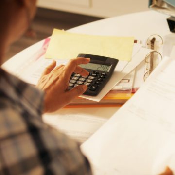 Elderly Woman Using Calculator For Taxes And Budget At Home Utilidades 2021: ¿Cómo debo administrar este ingreso extra?