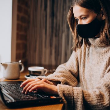 Young woman working on laptop in a cafe wearing mask Conoce el perfil de las madres emprendedoras en tiempos de Covid-19
