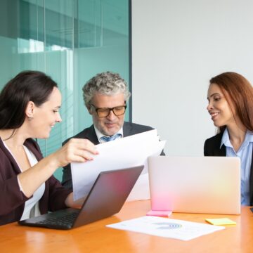 Managers presenting paper reports to boss Anticiparse a los escenarios: ¿qué es el futuring y por qué marca una ventaja competitiva para los ejecutivos y empresas?