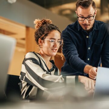 Two Colleagues Working On Laptop in Office. Female Hispanic Help SAP adquiere Reltio: Preparando datos SAP y de otras fuentes para la IA